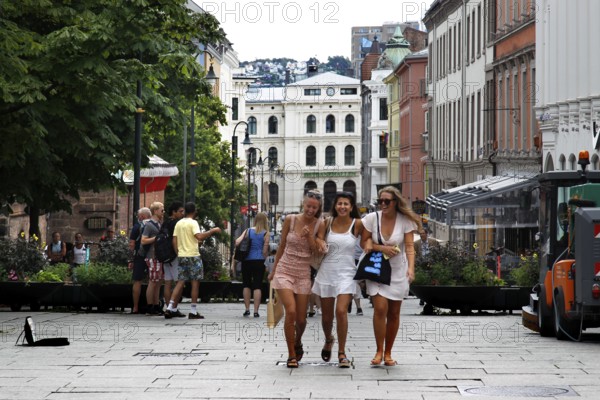 Three woman happily stroll along the busy Karl Johans gate in Oslo, Oslo, Norway