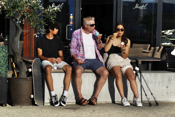 Passers-by sit and enjoy ice cream on summer day in Sørengkaia, Oslo, Oslo, Bispevika, Norway