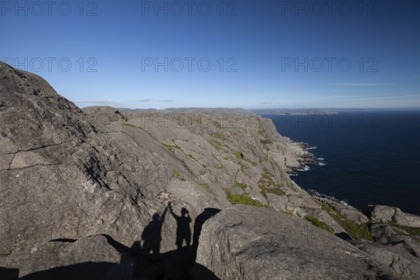 Shadow of two people giving a high five on a hiking trail view. Summer, Sandvika (Sandviga), Agder, Norway
