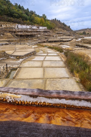 Traditional salt evaporation ponds creating white salt crystals and saline water, showcasing the ancient craft of salt production in the anana salt valley