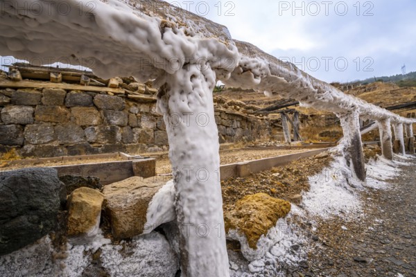 Salt covering the wooden structures and ground in the historic salt valley of anana, showcasing the traditional evaporation ponds for salt production in the basque country