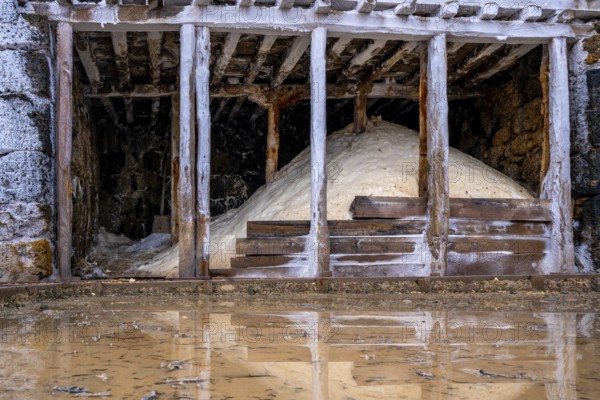 Salt piles stored inside traditional wooden structures at the anana salt valley, showcasing the artisanal salt production and harvesting process in spain's basque country