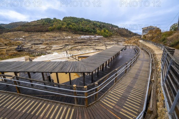 Salt evaporation ponds filling the salt valley of anana, showing traditional brine extraction methods and historic architecture with wooden walkways for visitors