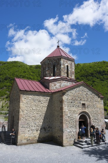 Stone church in rural area with visitors at the entrance under clear skies, Kvemo Mleta Lomis dome church, Kvemo Mleta, Mtskheta-Mtianeti region, Georgian Military Road, High Caucasus, Georgia