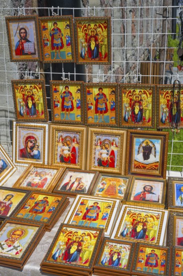Icons in various frames with bright colors depict religious figures at a market stand, stand in front of the domed church of Kvemo Mleta Lomis, Kvemo Mleta, Mtskheta-Mtianeti region, Georgian Military Road, High Caucasus, Georgia