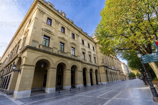 Gipuzkoa square facade in san sebastian with repeating stone arches and windows along a tree lined street, classic ornate architecture framing a peaceful urban scene