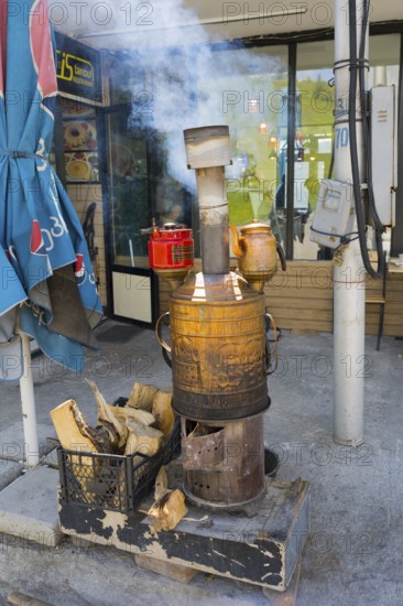 A smoking iron samovar stands in front of a café surrounded by wood, making tea near Gudauri, Mtskheta-Mtianeti region, Georgian Military Highway, High Caucasus, Georgia