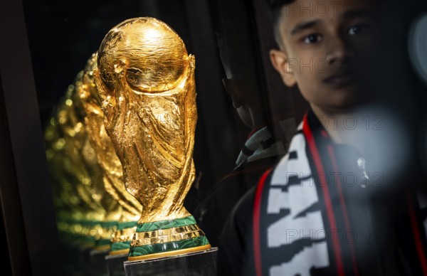 A football fan poses for a photograph with the original FIFA World Cup 2026 Trophy during the official India tour in Guwahati, Assam, India, on January 13, 2026