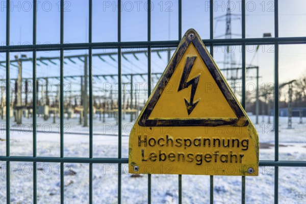 Recording of snow in winter warning sign warning high voltage danger to life on fence from behind substation substation substation substation part of electrical supply network with transformer generator in the background high-voltage lines high-voltage pole for secure energy supply Power supply, Germany
