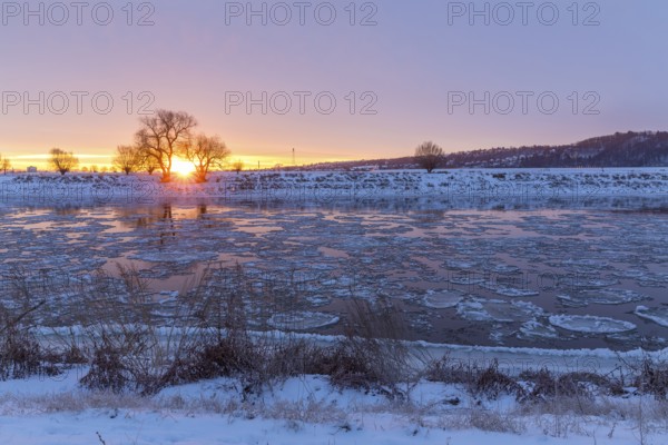 Cold winter morning on the Elbe with floating ice floes, snow and dawn at sunrise, Kötzschenbroda, Radebeul, Saxony, Germany