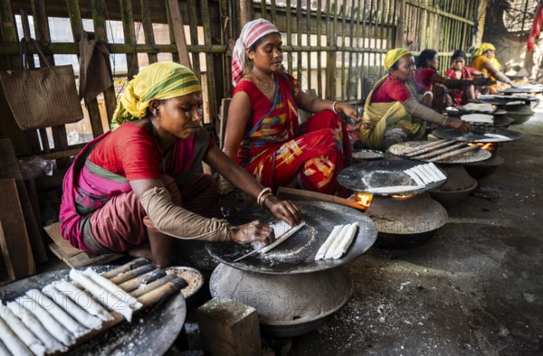 Women prepare 'Pitha', Assamese traditional rice-based sweets or snacks, as part of preparations ahead of the 'Magh Bihu' festival, in Guwahati, Assam, India on January 12, 2026. Magh Bihu, also called Bhogali Bihu, is Assam's harvest festival marking the end of the agricultural season and celebrated with feasts, community bonfires, and traditional food