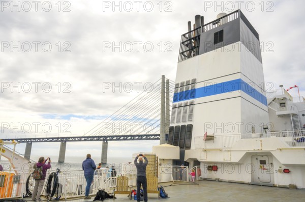 Passengers on a ship with a view of the Øresund Bridge, a ferry under a massive bridge structure of the Öresund Bridge in the background a chimney of the ship, Malmö, Øresund, Skane län, Sweden