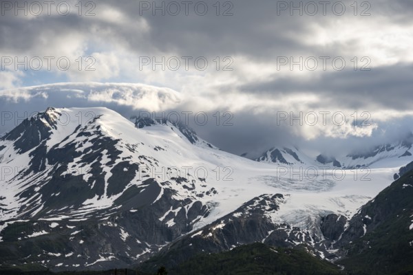 Mountain peak with Worthington Glacier glacier, dramatic cloudy sky, picturesque landscape on Richardson Highway, Chugach Mountains, Alaska, USA