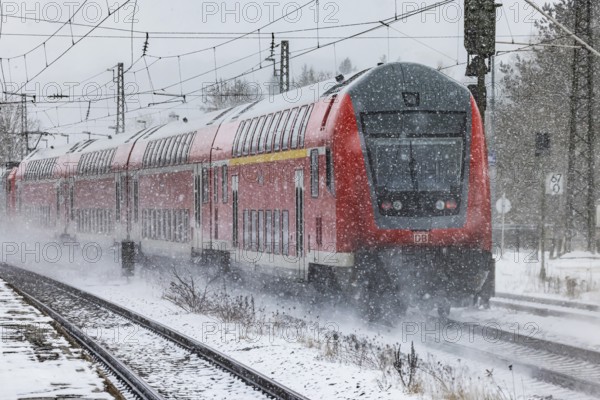 RegionalExpress RE on the road through a winter landscape in snowfall. A train on the line in the Deutsche Bahn AG rail network. Amstetten, Baden-Württemberg, Germany