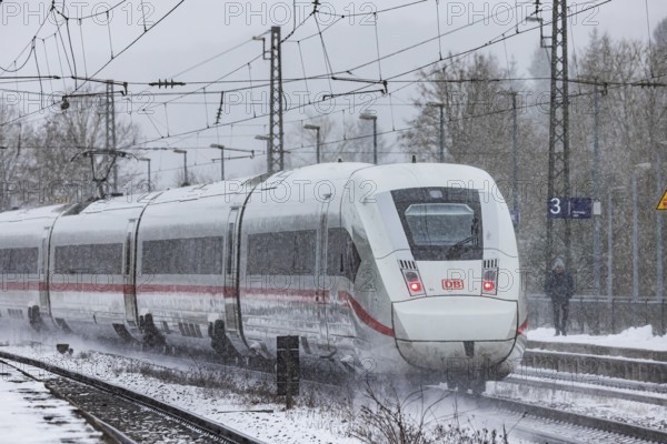 ICE traveling through a winter landscape in snowfall. A train on the line in the Deutsche Bahn Amstetten rail network, Baden-Württemberg, Germany