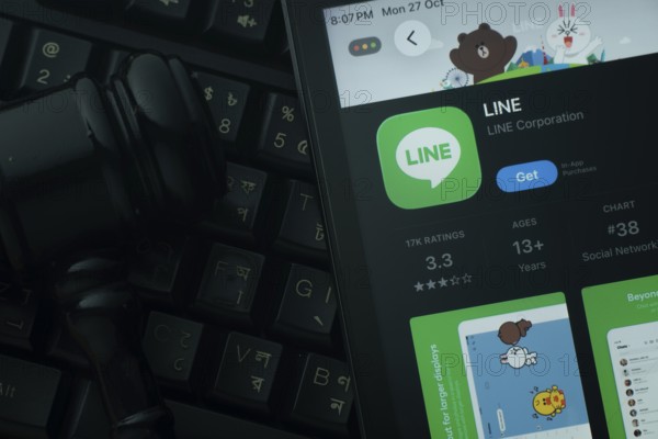 Dhaka, Bangladesh- 28 Oct 2025: An iPad displaying the LINE app against a judge's gavel and dark keyboard background