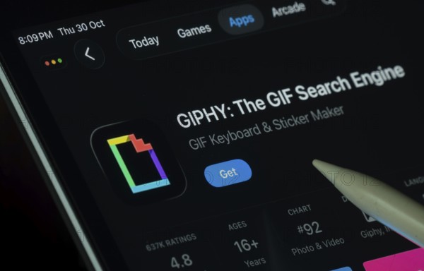Dhaka, Bangladesh- 30 Oct 2025: GIPHY app displayed on a iPad screen in dark mode with a digital pen pointing at it