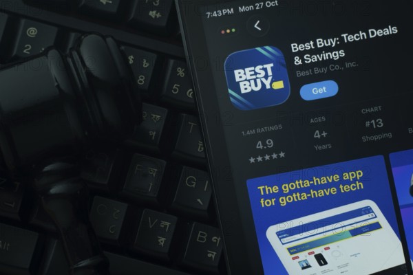 Dhaka, Bangladesh- 28 Oct 2025: An iPad displaying the Best Buy app against a judge's gavel and dark keyboard background