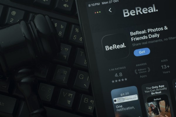 Dhaka, Bangladesh- 28 Oct 2025: An iPad displaying the BeReal app against a judge's gavel and dark keyboard background