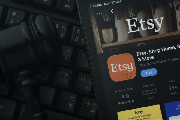Dhaka, Bangladesh- 28 Oct 2025: An iPad displaying the Etsy app against a judge's gavel and dark keyboard background