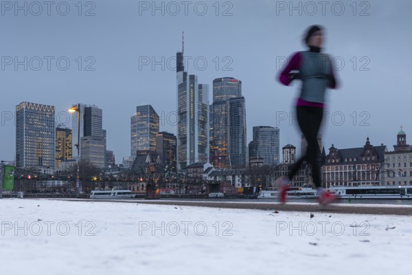 The towers of the Frankfurt banking skyline rise behind the snow-covered banks of the Main, Frankfurt am Main, Hesse, Germany