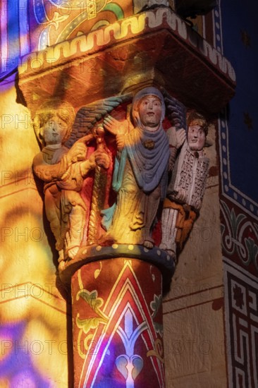 Issoire. Pillar (The Annunciation made to Mary) . The figures are illuminated by colorful light shining through a stained glass window inside Saint Austremoine Abbey, Puy de Dome, Auvergne Rhone Alpes, France
