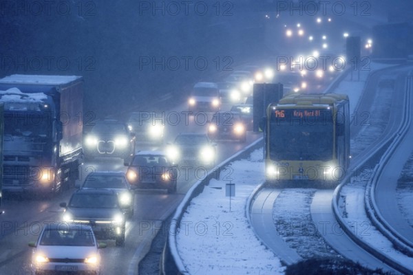 Winter weather, motorway traffic, A40 motorway, Ruhrschnellweg, in Essen, at the Essen-East motorway junction, snowfall, traffic jams, heavy flowing traffic, bus lane between roads, public transport, North Rhine-Westphalia, Germany