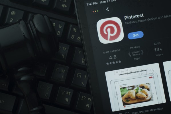 Dhaka, Bangladesh- 28 Oct 2025: An iPad displaying the Pinterest app against a judge's gavel and dark keyboard background