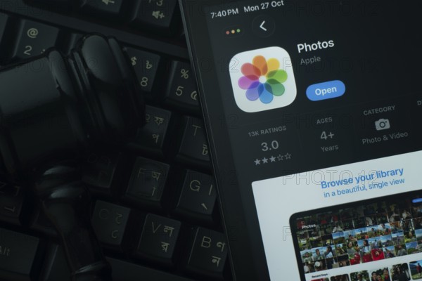 Dhaka, Bangladesh- 28 Oct 2025: An iPad displaying the Apple Photos app against a judge's gavel and dark keyboard background