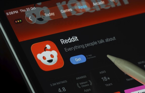 Dhaka, Bangladesh- 30 Oct 2025: Reddit app displayed on a iPad screen in dark mode with a digital pen pointing at it