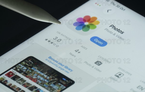 Dhaka, Bangladesh- 30 Oct 2025: Apple Photos app on a iPad screen with a pen pointing at the install option