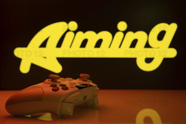 Dhaka, Bangladesh- 20 Mar 2025: A close-up of a white gamepad with the Aiming Inc seen on screen in the background