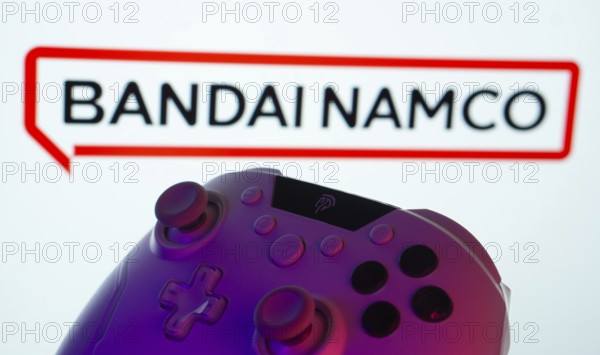 Dhaka, Bangladesh- 20 Mar 2025: A close-up of a gamepad with the Bandai Namco Entertainment seen on screen in the background