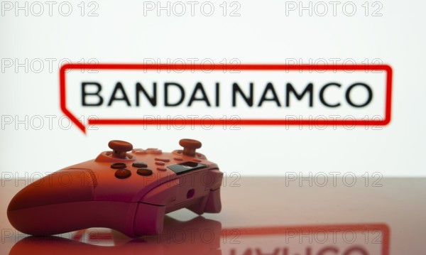 Dhaka, Bangladesh- 20 Mar 2025: A close-up of a white gamepad with the Bandai Namco seen on screen in the background