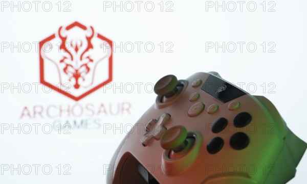 Dhaka, Bangladesh- 20 Mar 2025: A close-up of a gamepad with the ARCHOSAUR GAMES seen on screen in the background