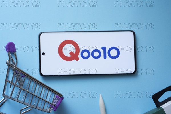 Dhaka, Bangladesh- 03 July 2025: Smartphone displaying Qoo10 logo with shopping cart on a blue background