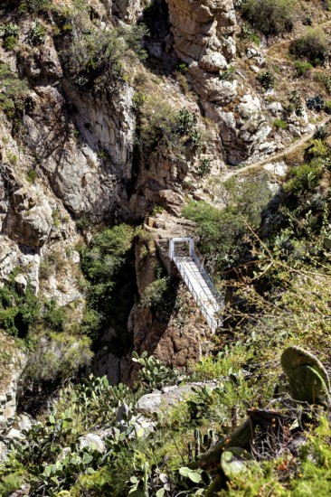 Suspension bridge that crosses a deep gorge between rocks, The landscape of the Colca Canyon in the Andes of Peru