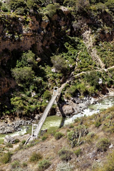 Wooden bridge over emerald-colored river, nestled in a rich rocky landscape, The landscape of the Colca Canyon in the Aden of Peru