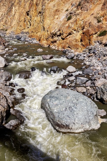 Close-up of a torrential river surrounded by boulders and orange cliffs, The landscape of the Colca Canyon in the Aden of Peru