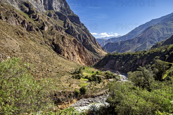 Wide valley with green vegetation and river, surrounded by imposing mountains, the landscape of the Colca Canyon in the Aden of Peru