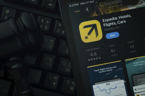 Dhaka, Bangladesh- 28 Oct 2025: An iPad displaying the Expedia app against a judge's gavel and dark keyboard background