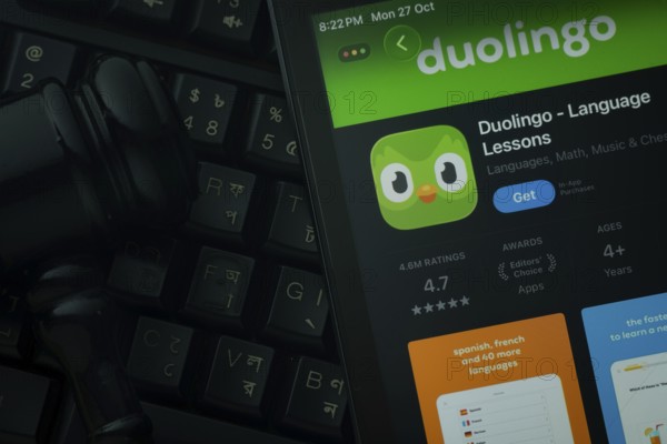 Dhaka, Bangladesh- 28 Oct 2025: An iPad displaying the Duolingo app against a judge's gavel and dark keyboard background