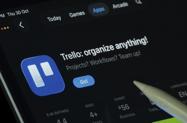 Dhaka, Bangladesh- 30 Oct 2025: Trello app displayed on a iPad screen in dark mode with a digital pen pointing at it