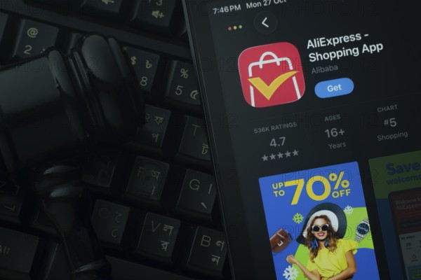 Dhaka, Bangladesh- 21 Nov 2025: An iPad displaying the AliExpress app against a judge's gavel and dark keyboard background