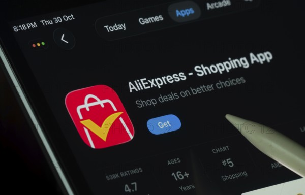 Dhaka, Bangladesh- 21 Nov 2025: AliExpress app displayed on a iPad screen in dark mode with a digital pen pointing at it