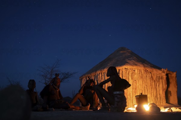 Himba at the campfire in the evening, night view, Himba huts, traditional Himba village in the savanna, Kaokoveld, Kunene, Namibia