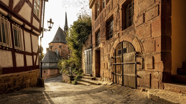 Historic old town alleyway with half-timbered houses and church in the warm light of sunset, The historic alleys and streets of the old town of Marburg