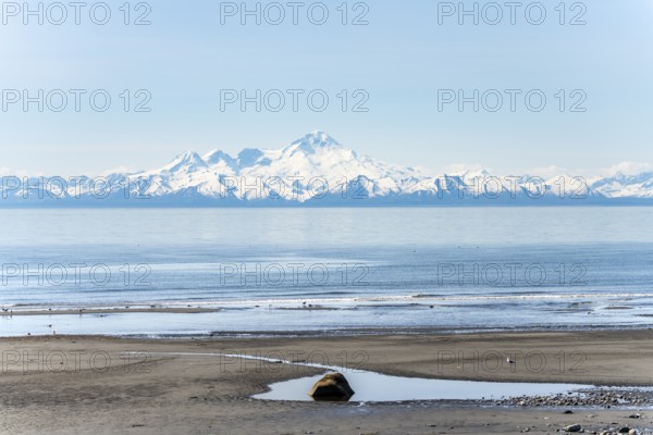 Beach at Anchor Point, Cook Inlet, glaciated mountain peaks of the Aleutian Range with Mount Iliamna summit, Anchor River State Recreation Area, Alaska, USA