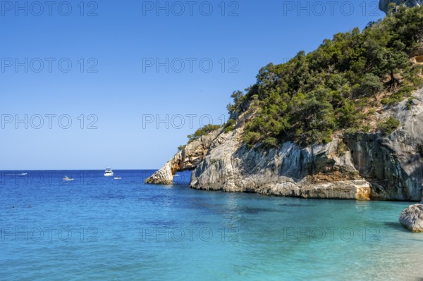 Light blue clear sea on a dream beach on Cala Goloritzé, picturesque rocky coast, cliffs with rock arch, Golfo di Orosei, Baunei, Sardinia, Italy