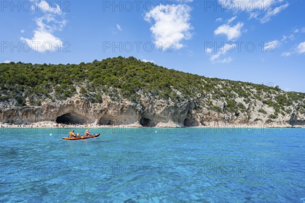 Kayakers in clear blue water, picturesque rocky coast, cliffs and Cala Luna beach, Golfo di Orosei, Baunei, Sardinia, Italy